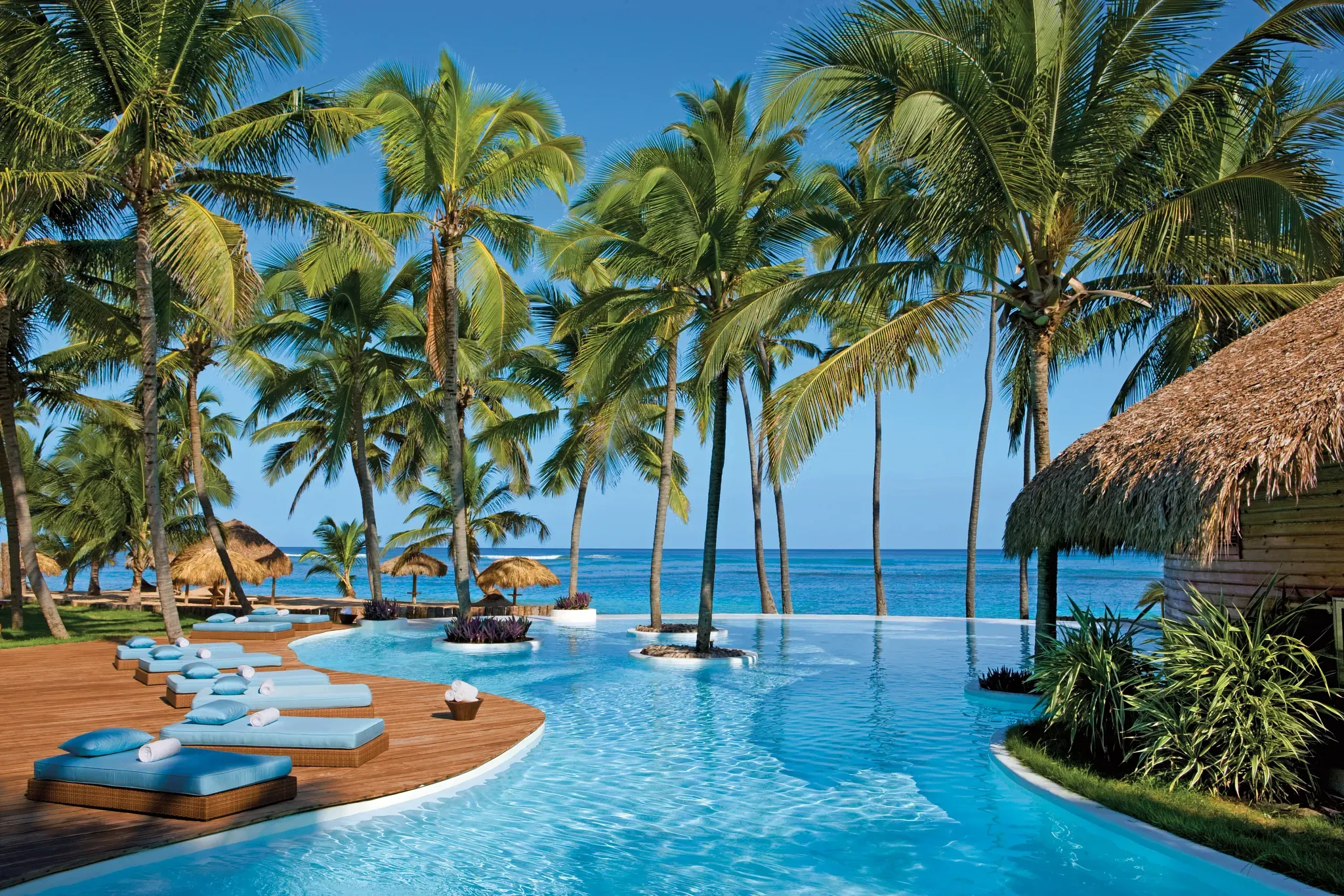 Luxuriöse Außenansicht des Zoëtry Agua Punta Cana Resorts in der Dominikanischen Republik mit Palmendächern und Pool – ein World of Hyatt All-Inclusive-Hotel.